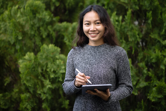 Asian creative professional portrait holding tablet and stylus in garden