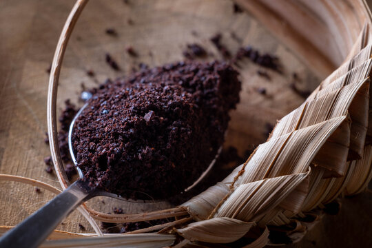 A spoon with ground roasted coffee on a wooden board with a braided decoration - Powered by Adobe