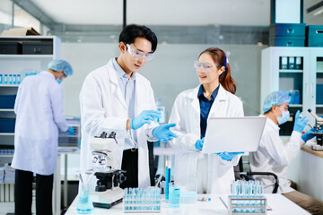 Scientists collaborating in a bright modern lab with blue liquids and microscopes, symbolizing teamwork, biotechnology, chemistry, and medical innovation.