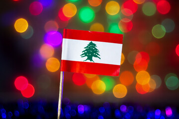 Lebanon national flag with its distinct green Cedar tree symbol against colorful festive bokeh lights. Symbolizing Middle Eastern culture, independence, Christmas, New Year, and global affairs.