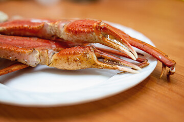 Boiled red crab claws on white ceramic plate, ideal for seafood cuisine photography and restaurant menu design