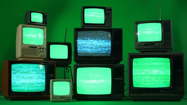 A collection of vintage televisions stacked together, all displaying green screens with static or a blank signal
