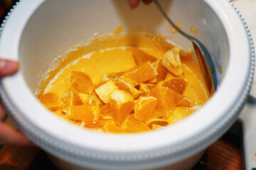 Diced orange flesh mixed in liquid batter for pie making, perfect for baking tutorials and dessert recipes