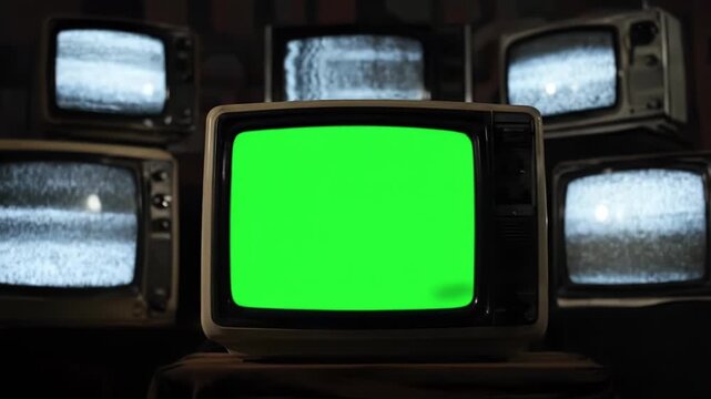 A collection of vintage televisions, some displaying static and one with a prominent green screen, creating a retro and nostalgic technological display