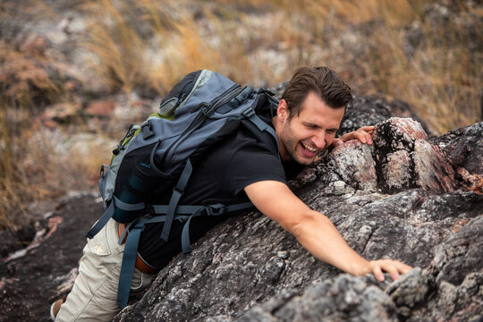Hiker man climbing natural rocky wall with tropical valley on the background. people backpack walking trail activity camping outdoors for destination leisure.