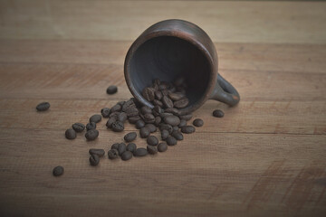 Coffee beans with a clay cup on a wooden table
