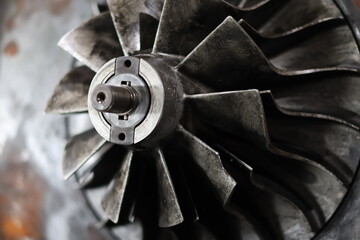 A close-up, high-angle view of a dirty, metallic turbine wheel with many sharp, angled blades, suggesting a part of a worn-out engine or turbocharger. © Jumain