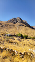 Arid autumn mountains with dry grasses, stone houses, and rocky slopes under a clear blue sky — a vivid glimpse of seasonal wilderness.  
📍Hazarani, Hawraman Takht 