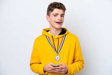 Teenager Russian man with medals isolated on white background surprised and sending a message