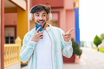 Handsome Arab man at outdoors listening music with a mobile and singing