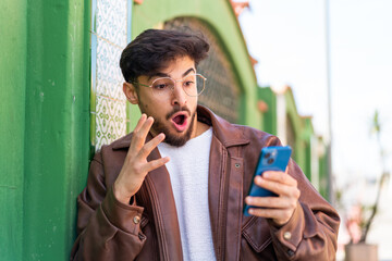Handsome Arab man at outdoors surprised and sending a message