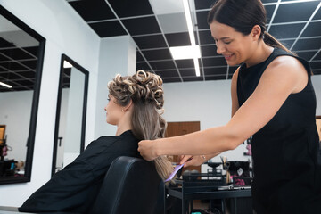 Hair stylist working on client’s hair in modern salon during daytime