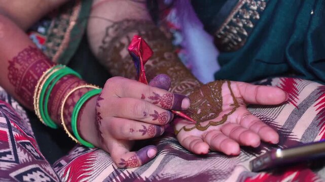 Skilled artist meticulously applies intricate traditional mehndi on a persons hand during an indian wedding ceremony.