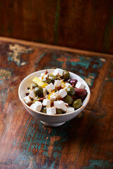 Green and kalamata olives and feta cheese on rustic wooden background. Soft focus.	
