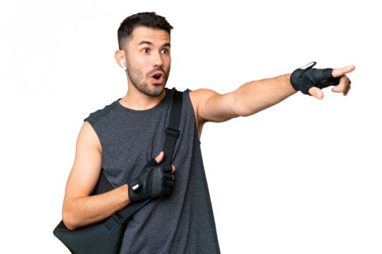 Young sport caucasian man with sport bag over over isolated chroma key background pointing away