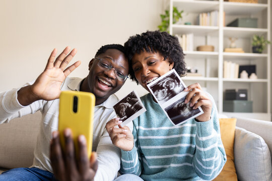 Excited couple sharing ultrasound scan on video call from home
