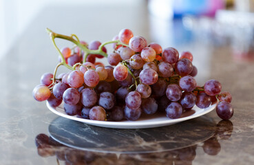 A bunch of purple grapes on a white plate