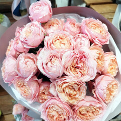 A beautiful bouquet filled with light pink and peach roses wrapped in light purple paper. Elegant floral gift for any occasion