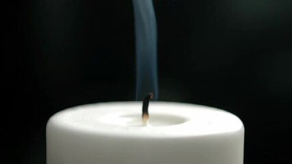 White candle extinguished with smoke creates a somber scene, white candle aftermath features faint wisps rising. Symbolic extinguished candle suggests peaceful moment or spiritual reflection.