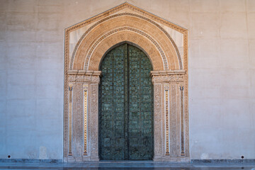 Ornate bronze doors at Monreale Cathedral with biblical scenes and decorative arch