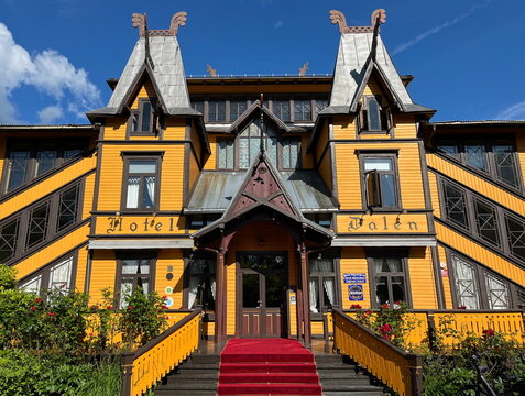 Dalen, Norway - July 27 2024: Entrance of the historic Dalen Hotel in Telemark, Norway. The yellow wooden building features traditional dragon-head roof decorations and red carpet stairs