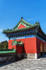 Fototapeta premium Traditional Chinese architecture at the Temple of Heaven, featuring vibrant red walls and distinct green-tiled roofs