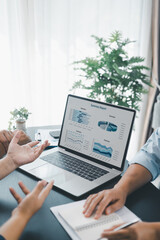 Business data analysis concept with colleagues reviewing financial report on laptop, pointing at chart with growth graph, teamwork discussing statistics, planning strategy and corporate success.