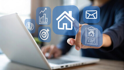 Professional hand touching virtual real estate icons on digital interface with laptop, representing property search, investment, online house buying, and modern real estate technology solutions.
