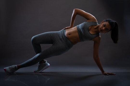 Young girl doing workout in active wear. Low key images. Studio light environment. Fitness freak young girl performing workout.