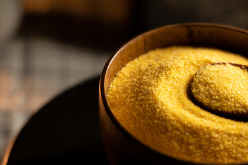 Corn grits in a wooden bowl with a wooden spoon ready for cooking today