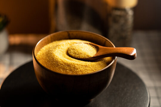 Corn grits in a wooden bowl with a spoon on a rustic table setting