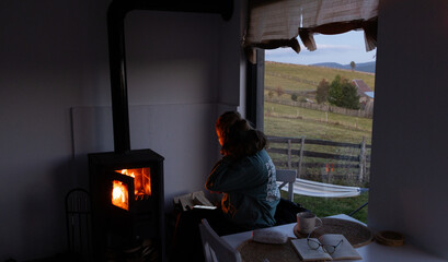 woman putting wood in fireplace cozy hygge living