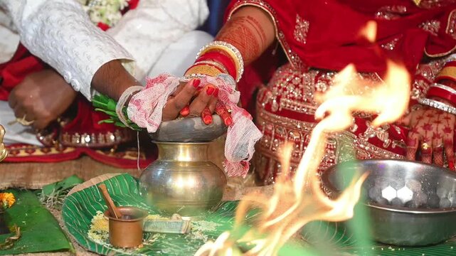 Hands of the bride and groom in wedding Ceremony. Hindu wedding ritual. Odia Wedding. Hindu Wedding Ceremony with Burning Fire and Offering Ritual with People and Golden Details.