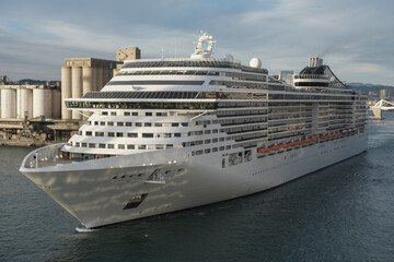 Massive Italian family cruiseship cruise ship Fantasia, Splendida or Divina in Barcelona, Spain during Summer Mediterranean cruising in sleek modern design with port infrasctructure and marine traffic