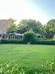 Historic Garden Courtyard with Green Lawn and Brick Architecture in Bright Sunlight