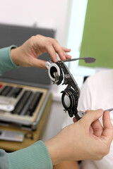 Trial frame for vision testing in a person's hands in an ophthalmology clinic.