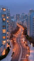 A High Angle View of a City Street at Dusk Lined With Tall Buildings Illuminated With Warm Lights and Glowing Windows With Distant City Lights Visible in the Background