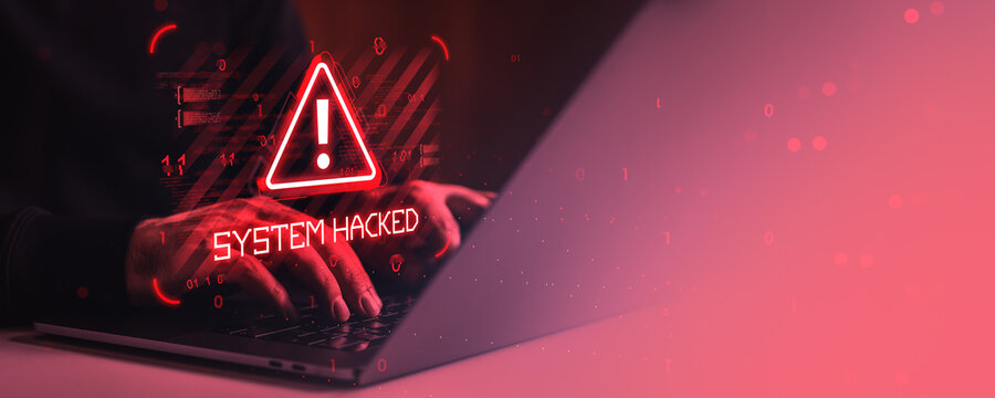 Cybersecurity warning with system hacked alert on laptop screen and hands typing in dark red digital environment with binary code overlay.