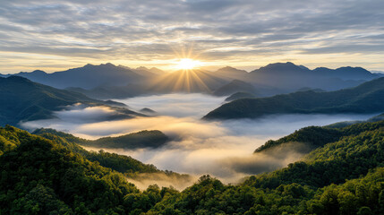 Obraz premium Golden sunlight breaks through clouds over misty mountain valley, creating serene atmosphere