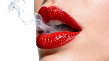 Close-up of a womans red lips exhaling smoke creating a mysterious and alluring visual.