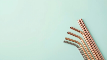 Set of reusable copper metal drinking straws on a pastel turquoise background, promoting a zero-waste and eco-friendly lifestyle