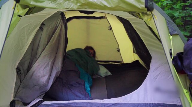 Girl hiking alone in a summer forest. Waking up in a tent