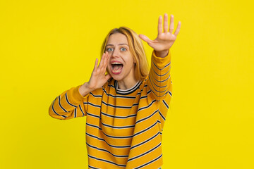 Expressive Caucasian young blonde woman holding hands near mouth loudly screaming, shouting, yelling, announces discounts sale Hurry up, welcomes someone hello. Girl isolated on yellow background