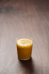 Mango lulo smoothie on walnut wood table with copy space