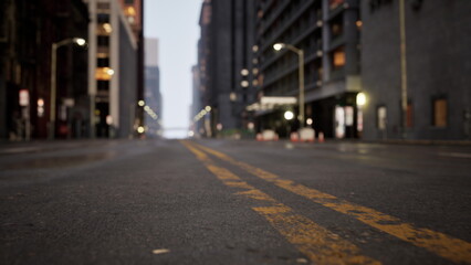 Early morning reveals a deserted street in an urban area. The soft glow from streetlights reflects on the damp pavement, creating a tranquil atmosphere in a bustling city.