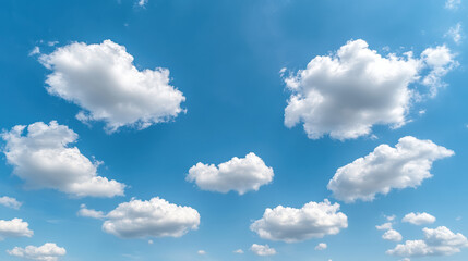 Fototapeta premium Fluffy white clouds float in bright blue sky, creating serene and peaceful atmosphere