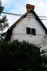 Quaint small house with triangular roof, brick chimney and wooden shutters under blue sky