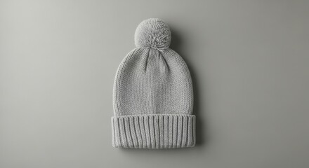 Gray knitted beanie with a pom-pom on neutral background  