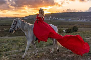 Woman horse sunset beautiful blonde rider in red flowing dress on white horse during golden hour
