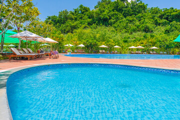 swimming pool at tropical luxury resort in summer. Tourism and recreation. Landscape with a pool and sun beds and umbrellas